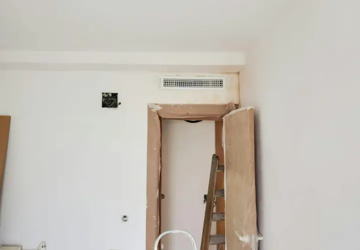 Instalación de rejilla para montaje de aire acondicionado sobre puerta en obra.