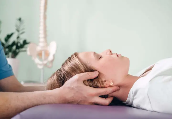 Delikatna terapia cranio sacralna u młodej dziewczyny. Terapeuta delikatnie uciska jej głowę, wspierając proces leczenia.
