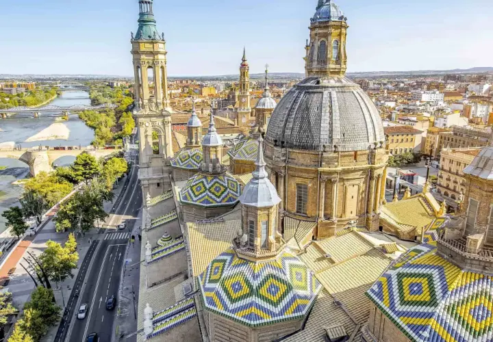 Vistas aéreas de la Basílica del Pilar en Zaragoza, con el río Ebro y puentes. Imagina un viaje en tren Sevilla Zaragoza para ver esta maravilla.