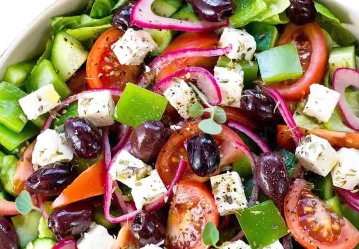 Insalata greca colorata con cubetti di feta, pomodori, olive, cetrioli e cipolla rossa. Il sapore fresco e mediterraneo è invitante.