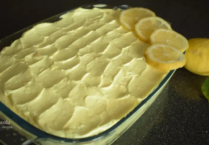 Tiramisù al limone pronto per essere gustato, decorato con fette di limone fresco e limoni interi.