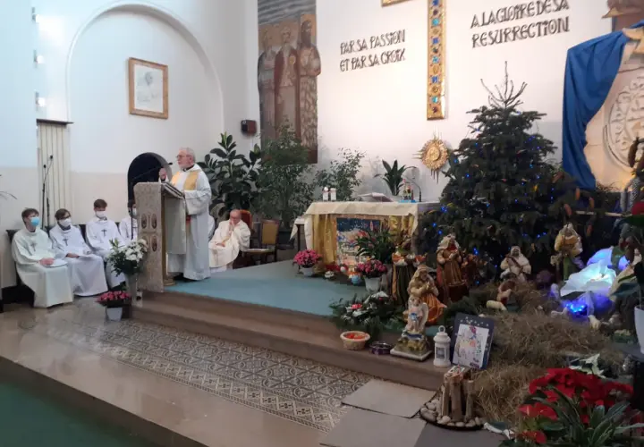 Uroczystość w kościele z kapłanem przy pulpicie i szopką bożonarodzeniową. Święta Genowefa w centrum uwagi.