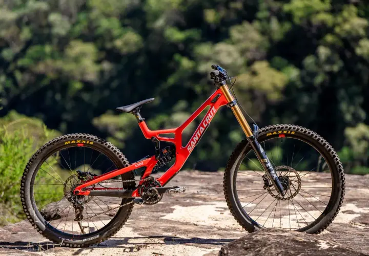 A bright red Santa Cruz V10 downhill bike sits on rocks, ready for its next review.