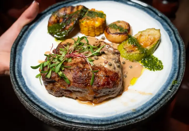 Un succulent filet mignon barbecue, nappé d'une sauce crémeuse aux poivres, accompagné de légumes grillés et de maïs.