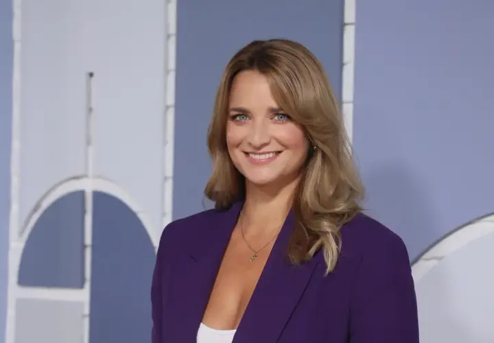 Dagmara Kaczmarek Szałkow w fioletowej marynarce, znana z Faktów TVN, uśmiecha się do kamery.