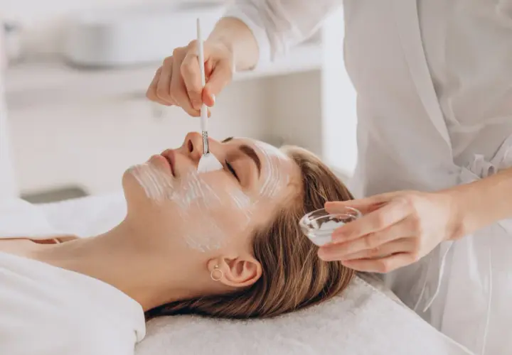 Delikatny peeling enzymatyczny w ciąży. Kosmetolog nakłada maskę na twarz kobiety, dbając o jej komfort i bezpieczeństwo.