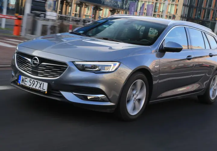 Szary Opel Insignia 2.0 CDTI w wersji kombi jedzie po miejskiej drodze.