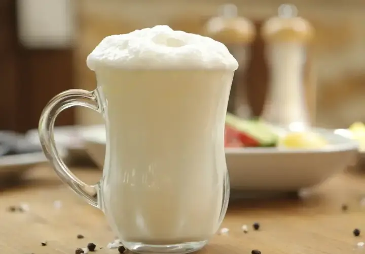 Puszysty ayran w szklance, idealny napój na upalne dni. Czy wiesz, ayran co to? To orzeźwiający napój jogurtowy.
