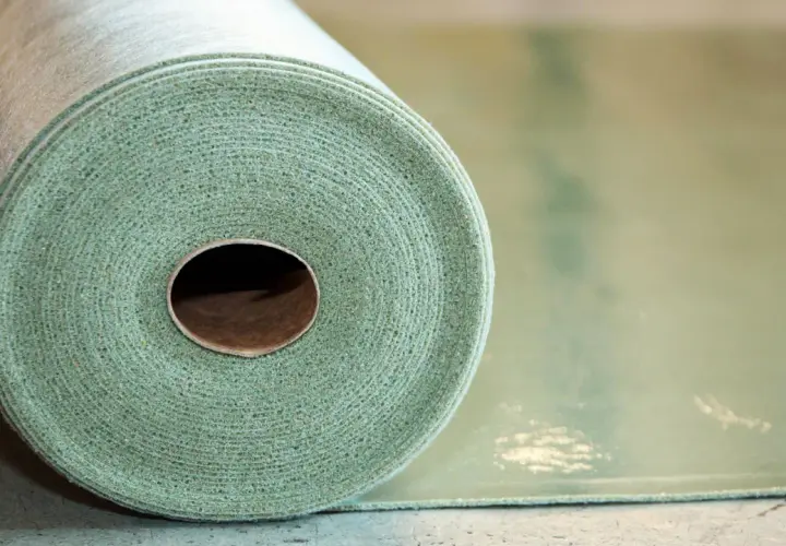 Rotolo di materiale per insonorizzare pavimento, con texture fibrosa e colore verde chiaro.
