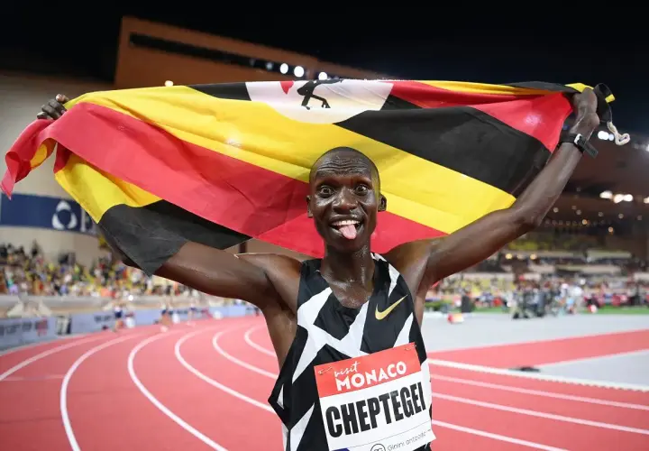 Joshua Cheptegei z flagą Ugandy świętuje swój rekord świata na 5km.