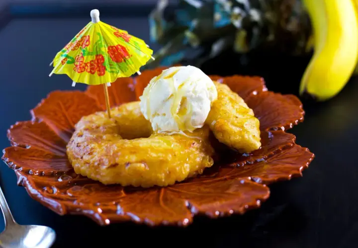 Friterad banan med vaniljglass och en liten parasoll på en vacker tallrik. En härlig dessert!