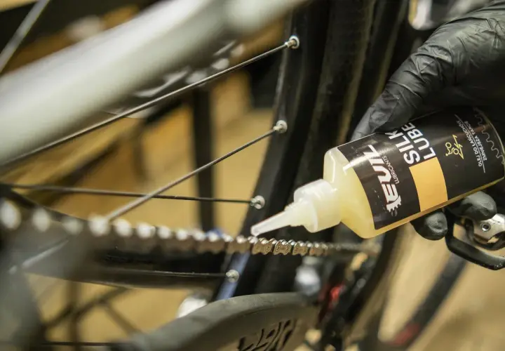 Rękawiczka z czarną rękawiczką aplikuje olej do łańcucha rowerowego. Jaki smar do łańcucha rowerowego wybrać? Ten "Silk Lube" wygląda obiecująco.