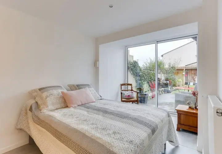 Chambre lumineuse avec vue sur jardin, résultat d'une belle idée : transformer un garage en habitation. Lit douillet, mobilier cosy.