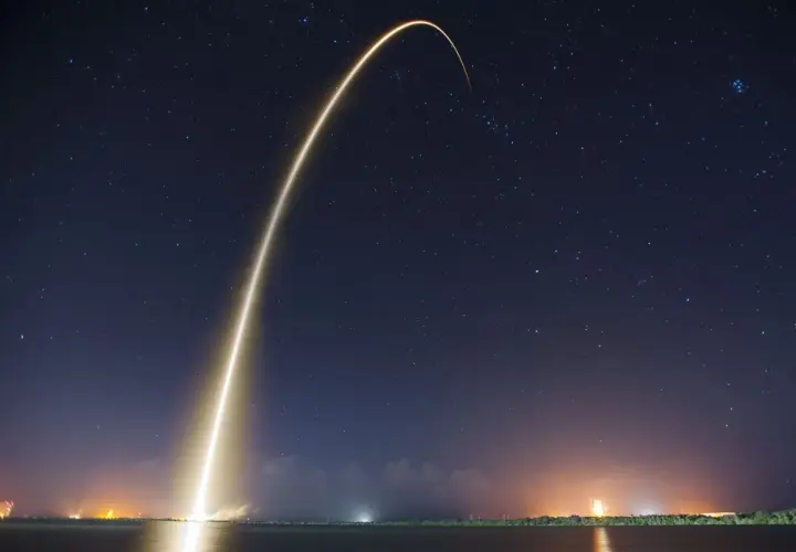 Jasny ślad rakiety wznosi się na nocne, gwieździste niebo, symbolizując start Starlink Elona Muska.