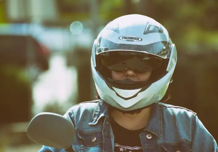 Motociclista con casco jet, che offre una visione chiara, a differenza di un casco demi jet. Indossa giacca di jeans.