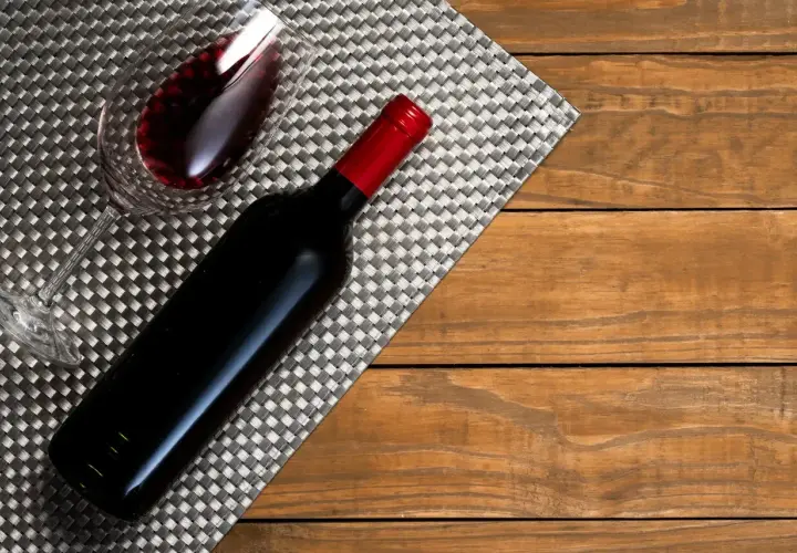 Ciemnoczerwone wino w kieliszku i butelce, gotowe do degustacji przez sommeliera.