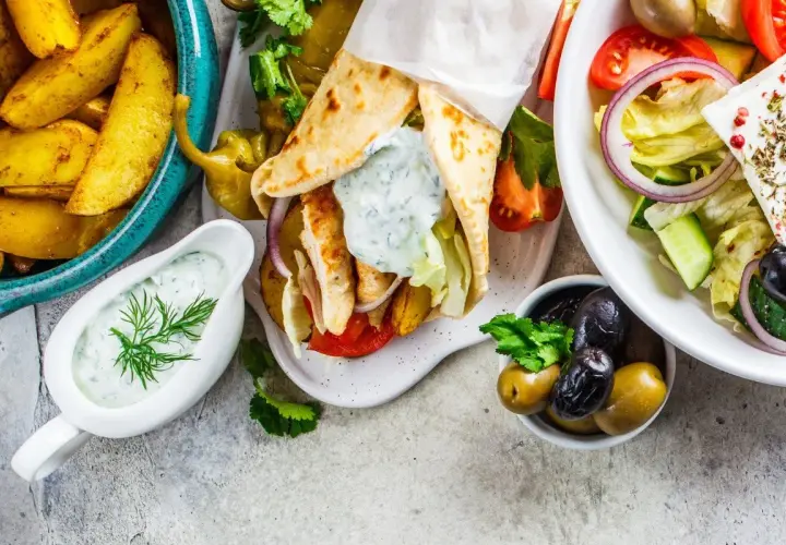Pyszne greckie danie: gyros w picie, frytki, sałatka grecka z fetą i oliwkami, sos tzatziki.