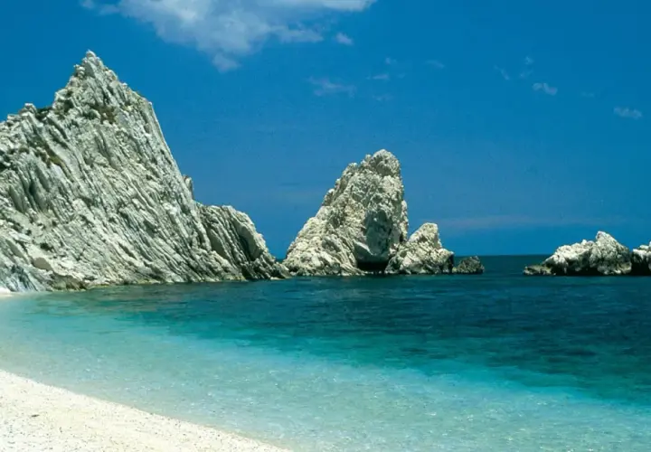 Spiaggia bianca e mare cristallino con faraglioni imponenti, un sogno per le vacanze Marche mare.