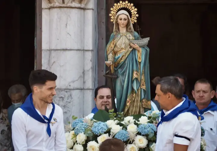 Procesión de la Virgen de la Guía, con hombres portando la imagen adornada con flores.