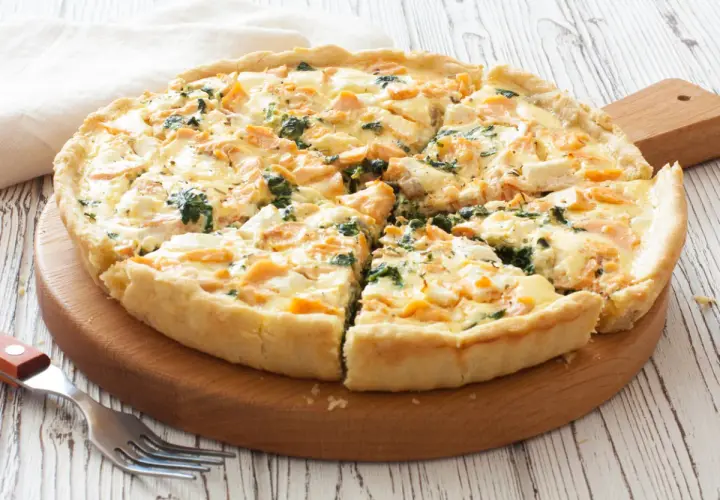 Pyszna tarta z łososiem, szpinakiem i serem feta, pokrojona na kawałki, gotowa do podania.