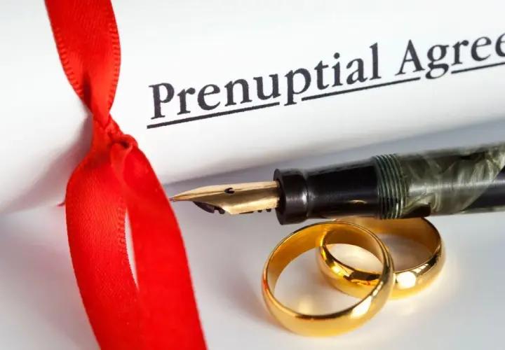 Złote obrączki i pióro na dokumencie "Prenuptial Agreement". Rozdzielność majątkowa koszt to ważna decyzja.