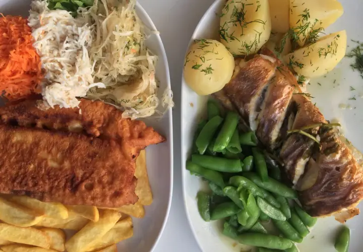 Dwa talerze pysznego jedzenia, idealne pytanie: gdzie zjeść w Gdyni? Ryba z ziemniakami i fasolką, a obok panierowany filet z frytkami i surówkami.