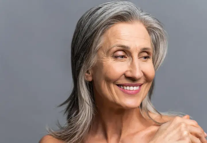 Mujer sonriente con cabello plateado, sus canas brillan con sabiduría y experiencia.
