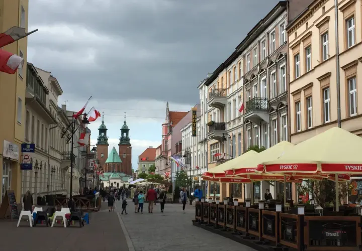 Spacer po Gnieźnie, gdzie widać zabytkowe kamienice, katedrę i flagi. To świetne gniezno atrakcje.