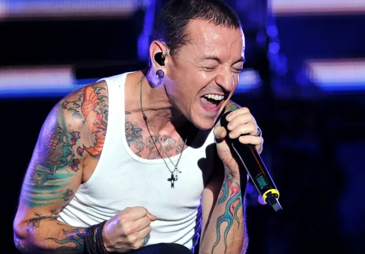 Chester Bennington, wokalista zespołu, śpiewa z pasją na koncercie. Jego ramiona pokryte są kolorowymi tatuażami.