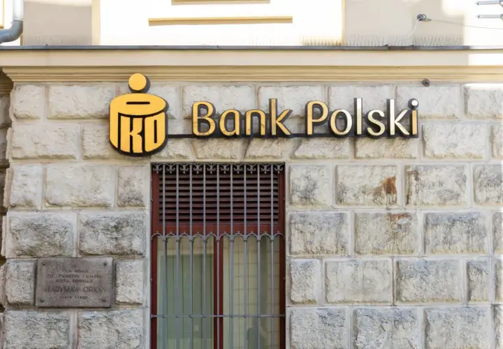PKO Bank Polski oferuje pko kredyt hipoteczny bez wkładu własnego. Złote logo banku na kamiennej fasadzie.