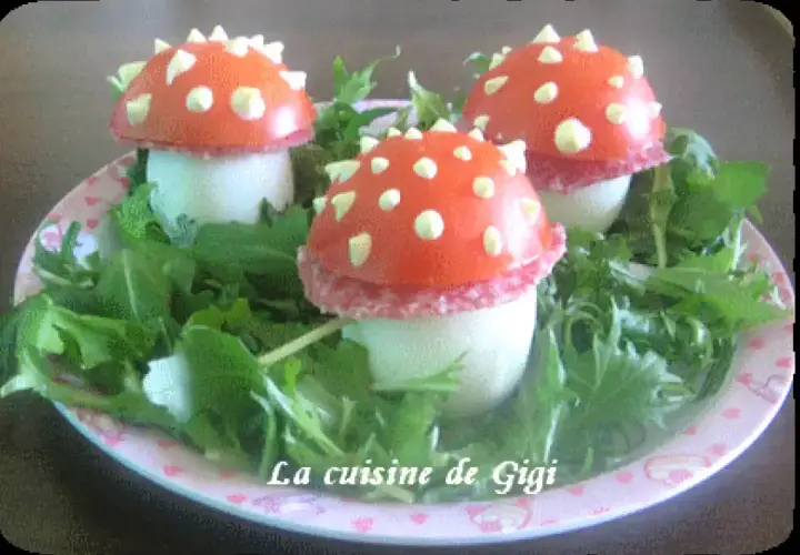 Trois adorables champignon œuf, décorés de tomate et de points blancs, reposent sur un lit de verdure.