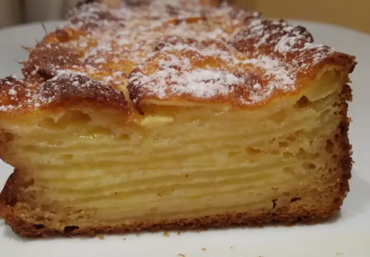 Une tranche de gâteau aux pommes, avec des couches fines et dorées, saupoudrée de sucre glace. Un délice invisible aux pommes.