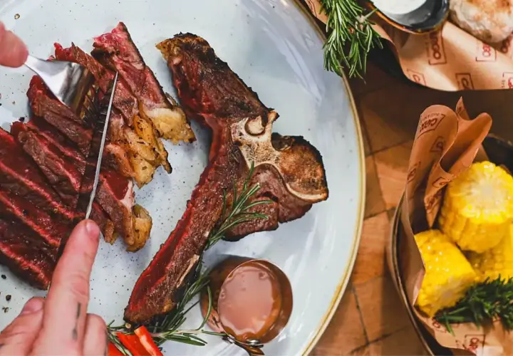 Soczysty stek T-bone, pokrojony w plastry, z pieprzem i rozmarynem. Idealny wybór, jeśli zastanawiasz się, jakie wino do steka.