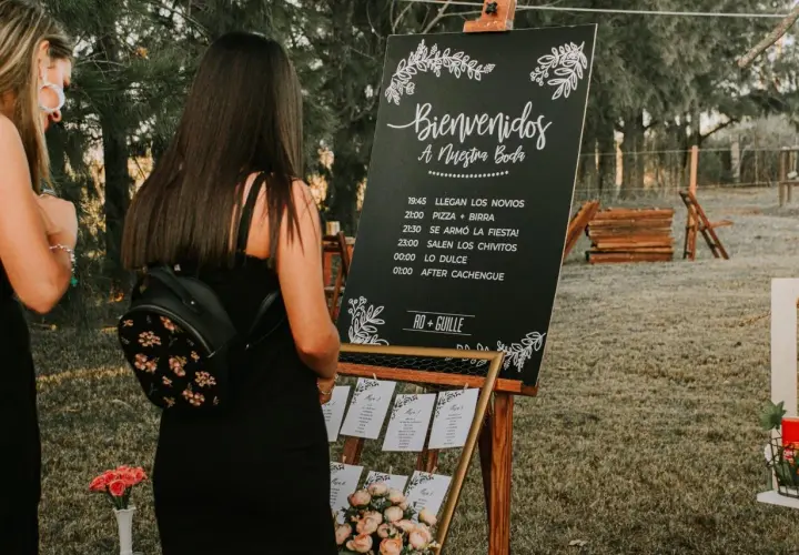 Cartel sobremesa de bienvenida a una boda con horarios y nombres de los novios.
