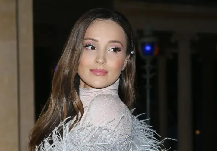 Elegancka żona Szczęsnego w błyszczącej sukni z piórami, z delikatnym makijażem i perłową spinką we włosach.