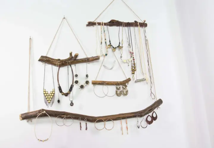 Colgante rústico con ramas de madera, ideal para exhibir collares y pendientes. Un ejemplo de manualidades de madera para adultos, con un toque bohemio.