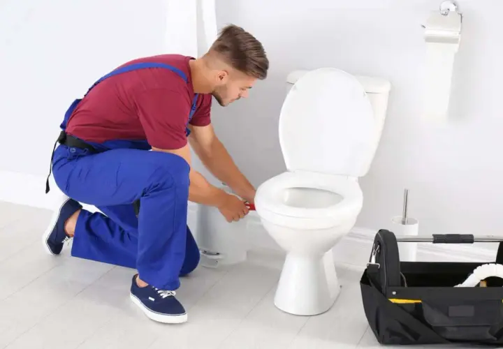 Idraulico al lavoro per sostituire guarnizione scarico WC. Attrezzi a portata di mano.