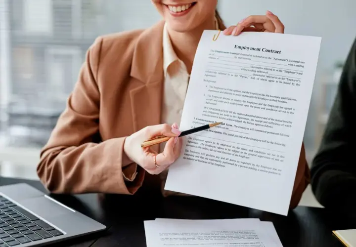 Persona sonriente muestra un contrato de empleo, lista para firmar contrato.