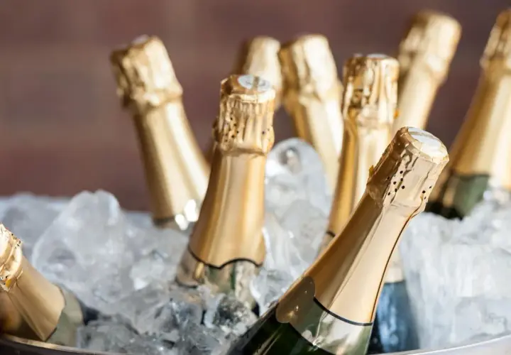 Mehrere Champagnerflaschen in goldenen Kapseln kühlen in einem Eisbad. Perfekt, um zu lernen, wie man Champagner trinkt.