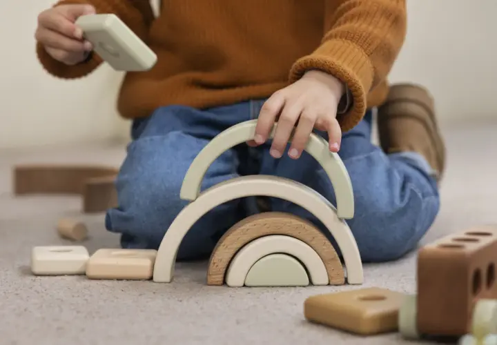 Niño jugando con bloques de madera, creando un arcoíris. Un ejemplo del sistema montessori para el desarrollo infantil.