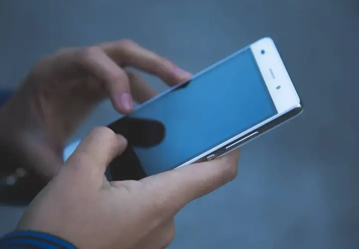 Dłonie trzymające smartfon. Zastanawiasz się, jak odzyskać telefon zatrzymany przez policję?