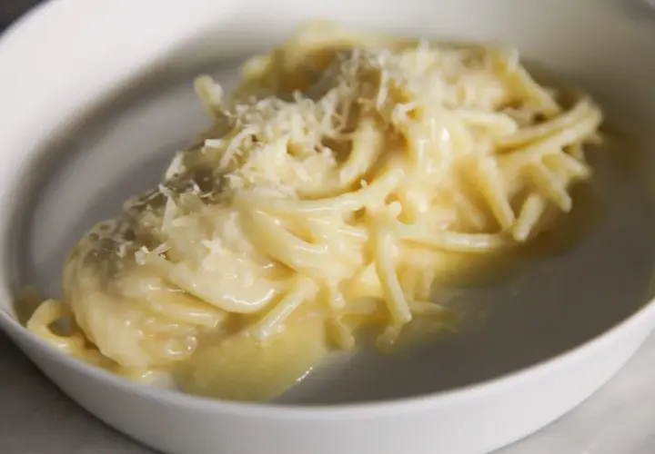Un piatto di pasta burro e parmigiano, cremoso e invitante, con una spolverata di formaggio grattugiato.