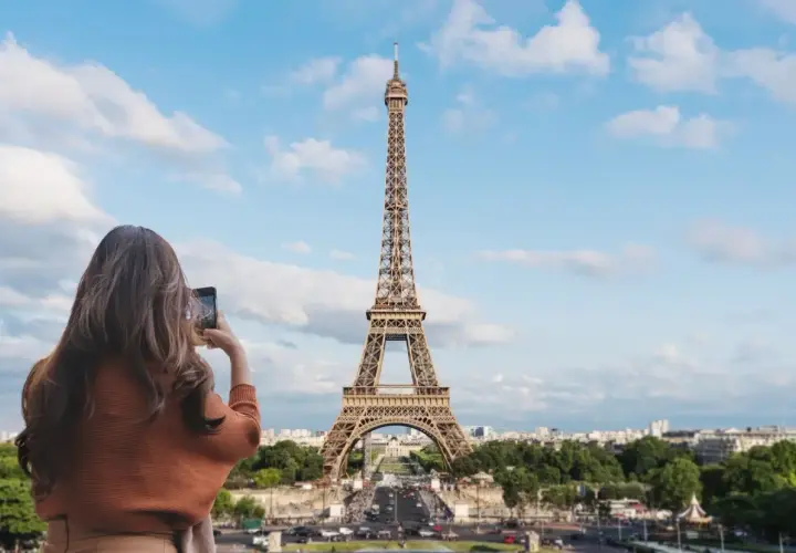 Kobieta robi zdjęcie telefonem ikonicznej wieży Eiffel.
