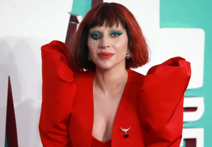 Lady Gaga w czerwonym, teatralnym stroju z niebieskim makijażem oczu i łzą na policzku. Fani marzą o koncercie Lady Gaga w Polsce.