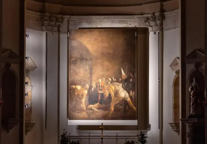 Il Seppellimento di Santa Lucia, capolavoro di Caravaggio in Sicilia, illuminato nell'oscurità di una chiesa.