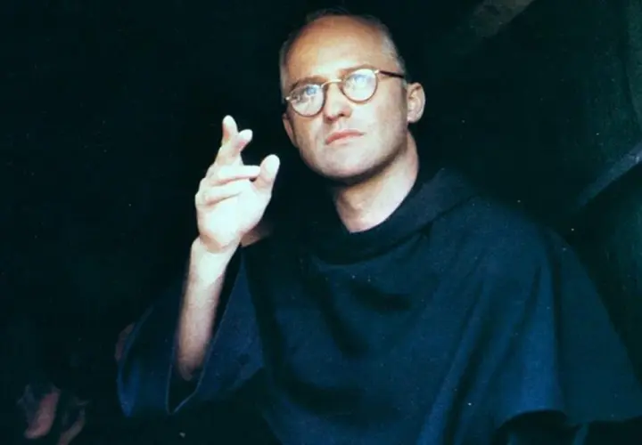 Aktor w filmie o Maksymilianie Kolbe, w okularach i habicie, gestykuluje.
