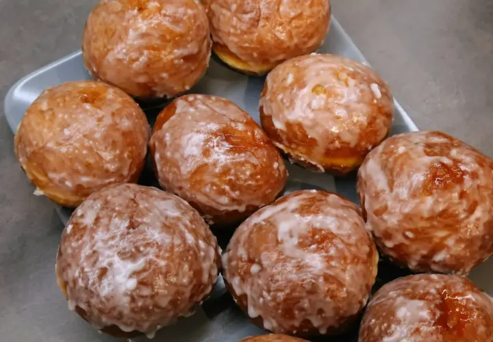 Szybkie pączki z piekarnika, oblane lukrem, kuszą swoim apetycznym wyglądem. Idealne na szybką przekąskę.