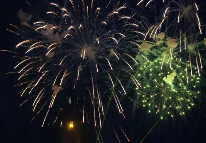 Pokaz sztucznych ogni nad ciemnym niebem, z widocznym fragmentem wieży.