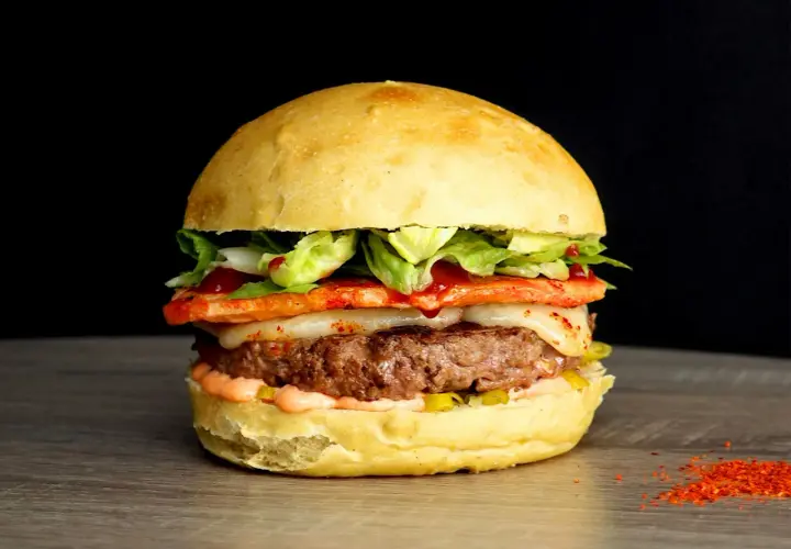 Un généreux burger savoyard avec un steak juteux, fromage fondant, légumes frais et une touche de piment sur un pain brioché.