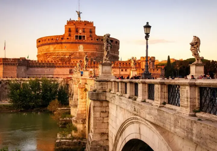 Le pont Saint-Ange à Rome, orné de statues d'anges, mène au château Saint-Ange au coucher du soleil.
